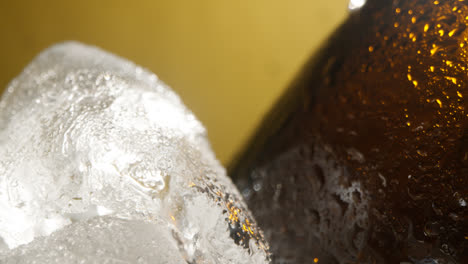 Primer-Plano-De-Gotas-De-Condensación-Corriendo-Por-Botellas-De-Vidrio-De-Cerveza-Fría-O-Refresco-Enfriándose-En-Un-Cubo-Lleno-De-Hielo-Contra-Fondo-Amarillo-2